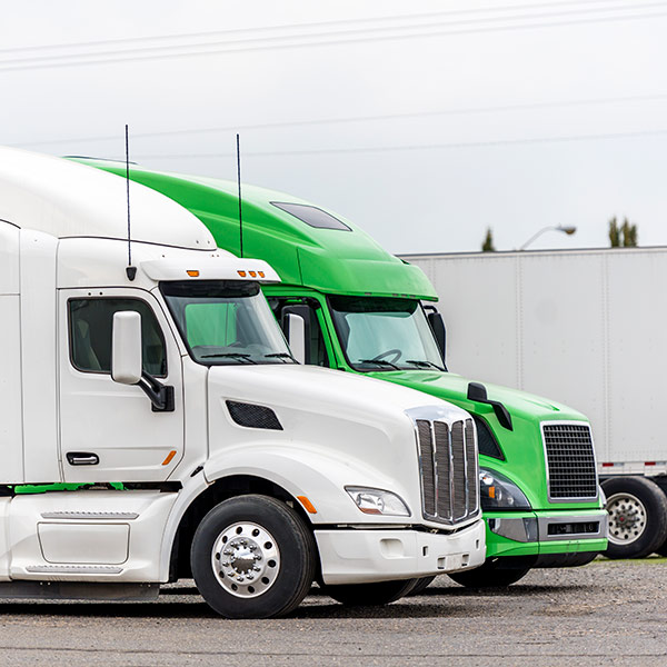 A green and a white trailer truck parked