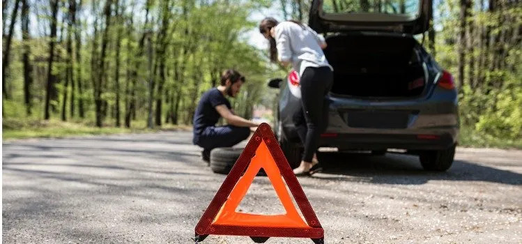 Couple Performing Roadside Assistance by Changing a Flat Tire on the Road