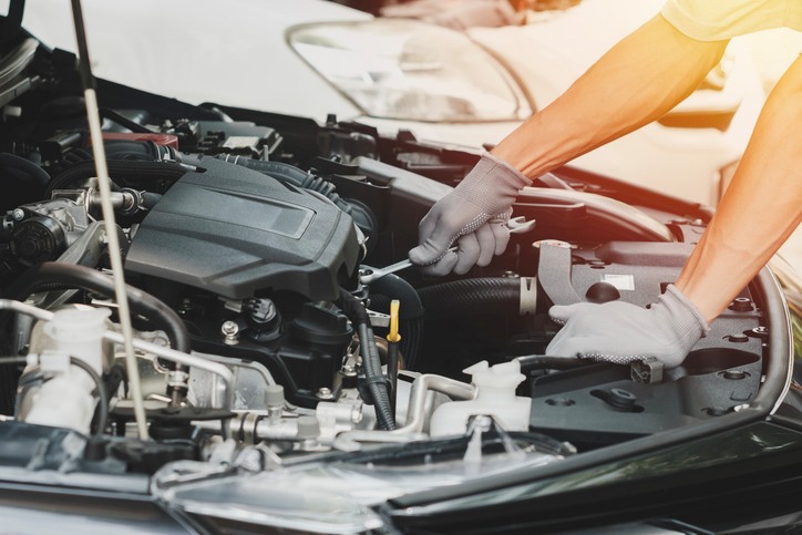 A Person repairing a car engine with gloves on in Greenville, SC