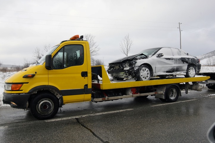 Damaged car being transported on a yellow tow truck in Greenville, SC