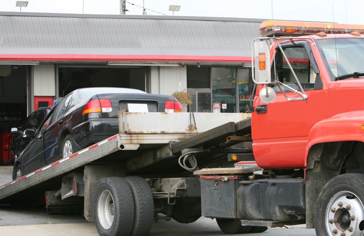 A tow truck is loading a black car onto a flatbed in Greenville, SC